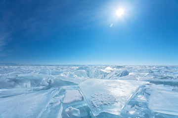 Bright winter sun over a field of ice hummocks with transparent pieces of blue ice. The magnificent...