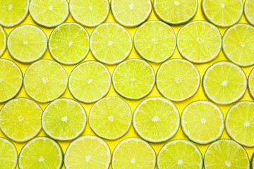 Juicy fresh lime slices on yellow background, flat lay