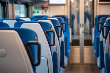 Inside cabin of modern express train.  Empty class two car with comfortable blue chairs, glass doors, monitor and safety equipment. Carriage interior.