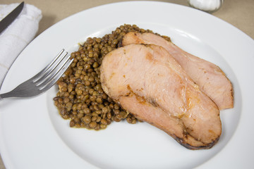 slices of roast pork and lentils on a plate