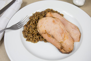 slices of roast pork and lentils on a plate