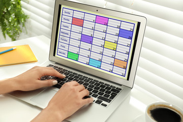 Young woman using calendar app on laptop in office, closeup