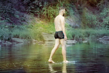 man in swimming trunks is on the surface of the water. concept of enlightened spirit and super ability. toned
