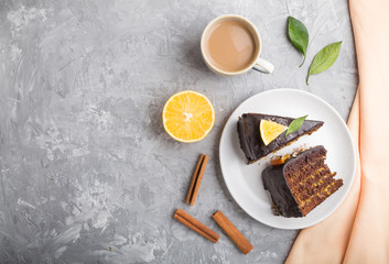 Homemade chocolate cake with orange and cinnamon with cup of coffee on a gray concrete background. top view, copy space.
