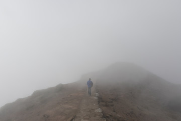 A man walking through thick fog on a mountain in Madeira, Portugal