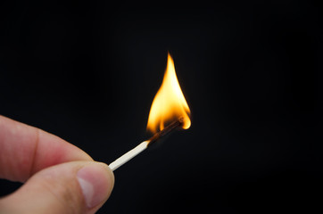 burning match in hand on a black background. Close-up.