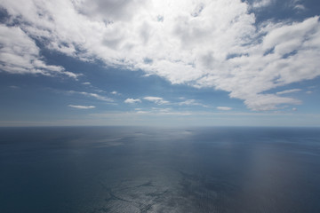 Clear blue ocean with sunny skies and white clouds above
