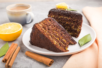 Homemade chocolate cake with orange and cinnamon with cup of coffee on a gray concrete background. side view, selective focus.