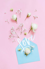 Flowers, envelope and word LOVE on a light pink background