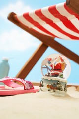 Souvenir santa snow globe under deckchair on beach close up