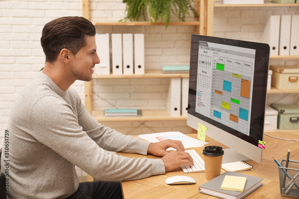 Canvas Prints Handsome man using calendar app on computer in office