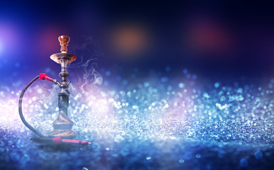 Hookah with smoke on a background of blurry lights. Abstract background, neon glow