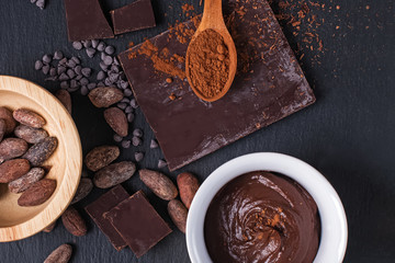 Cocoa beans, chocolate ganache, powder and chocolate pieces on black background,
