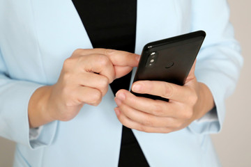 Woman using mobile phone, elegant girl in office suit stands with smartphone in hands. Concept of businesswoman, sms, online