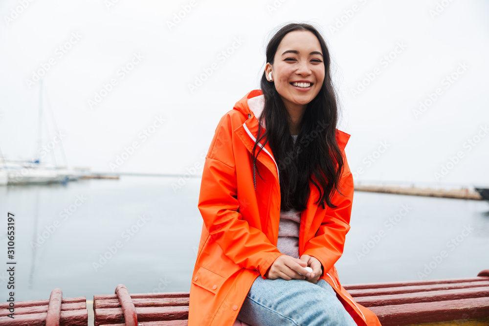 Wall mural smiling attractive young asian woman wearing raincoat