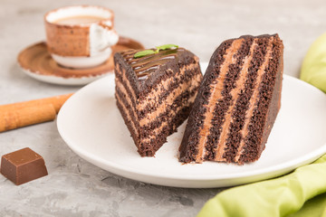 Homemade chocolate cake with milk cream and a cup of coffee on a gray concrete background. side view, selective focus.