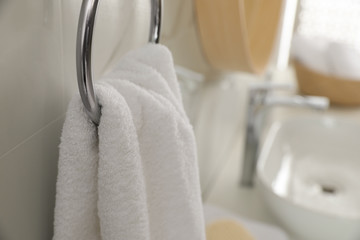 Obraz na płótnie Canvas Holder with clean towel on light wall in bathroom, closeup