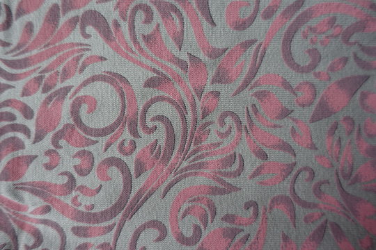 Top view of grey cotton fabric with pink scroll pattern