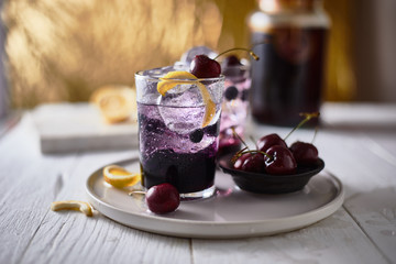 Fresh blueberry cocktail with lemon peel and cherry..