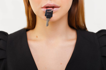 Closeup portrait of woman silent with a key in her mouth. Women's secrets. Silence is golden.