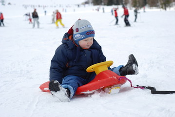 Fototapeta na wymiar winter, snow, child, boy, fun, cold, children, sled, kid, sledge, happy, people, sledding, family, childhood, playing, outdoors, sport, white, little, young, happiness, joy, play, sleigh