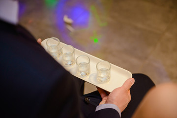 Bottle of cold vodka and wine bottle in bucket with ice and orange juice in jug on table, copy space. Alcohol bottles in ice bucket in restaurant. Wedding party.