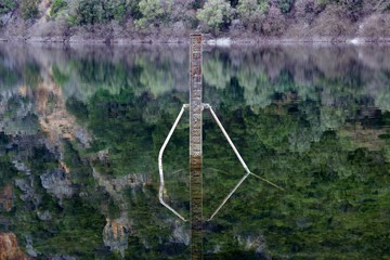 Depth instrument meter in a lake. Blurry reflections of  trees at the surface of the calm water. Soft focus at the background
