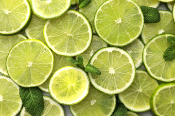 Fototapeta na wymiar Slices of fresh juicy limes as background, top view