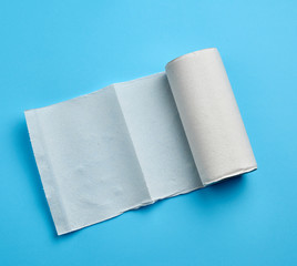twisted roll of white paper towel on a blue background. Paper sheet