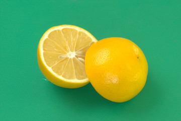 Lemon fruit. Fresh sliced citrus on green background. Yellow juicy fruit closeup. Natural vitamin C source.