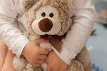 children's hands tightly hug the Teddy bear. the concept of kindness and tenderness. a child plays with a toy. beige bear with bow.