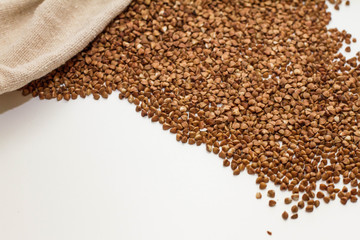 he scattered buckwheat on the white table. buckwheat grains on a white background. The view from the top. Space for text. delicious and healthy food and nutrition. vitamins for humans. cereals