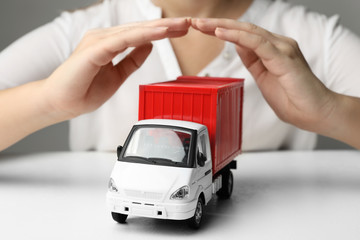 Woman covering toy truck at white table, closeup. Logistics and wholesale concept