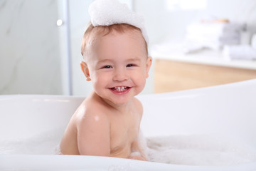 Cute little baby in bathtub at home