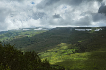 Alpine meadows. Shadow and sunlight. Green grass pasture.