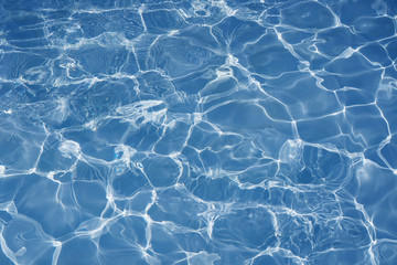 Blue water surface with bright sun light reflections. blue water in swimming pool background