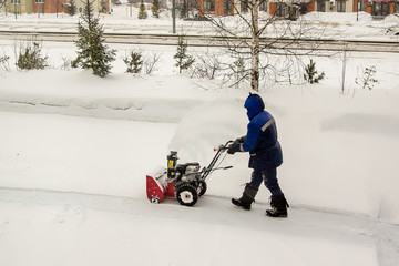 Fototapeta na wymiar worker removes snow from the yard using a snowplow