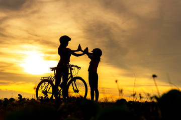 Obraz na płótnie Canvas Silhouette biker lovely family raise give me five at sunset for relax and freedom. Mom and daughter bicycling at the beach. Lifestyle Concept.