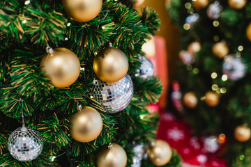 Obraz na płótnie Canvas Decorated Christmas tree on blurred background. Close-up mirror ball and gold balls ornament of Christmas tree decoration in sparkling and fairy background.