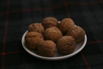 Inshell walnuts on a plate against a dark background