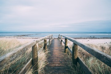 Wunderschöne Landschaft mit einem Holzweg, der zum Strand führt, um einen entspannten Tag zu verbringen?
