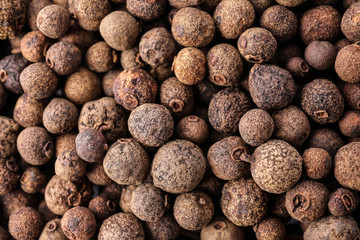Black pepper grains as background, top view