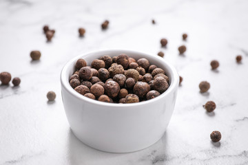 Black peppercorns in bowl on white marble table