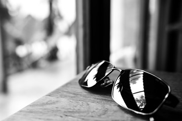 Single simple sun glasses on the wooden table with copy space, black and white color