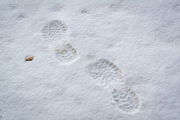 Imprints of shoes on white snow close-up.