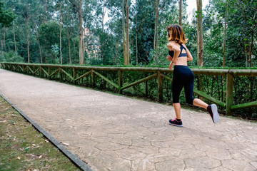 Unrecognizable athlete woman running through a park