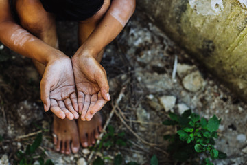 hands poor child or beggar begging you for help sitting at dirty slum. concept for poverty or hunger people,human rights,donate and charity for underprivileged children in third world 