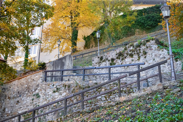 Staircase in the park with wooden railing and antique lanterns with stone walls in fall