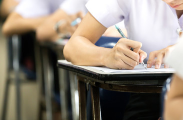 high school,university student study.hands holding pencil writing paper answer sheet.sitting lecture chair taking final exam attending in examination classroom.concept scholarship for education abroad