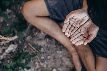 hands poor child or beggar begging you for help sitting at dirty slum. concept for poverty or...